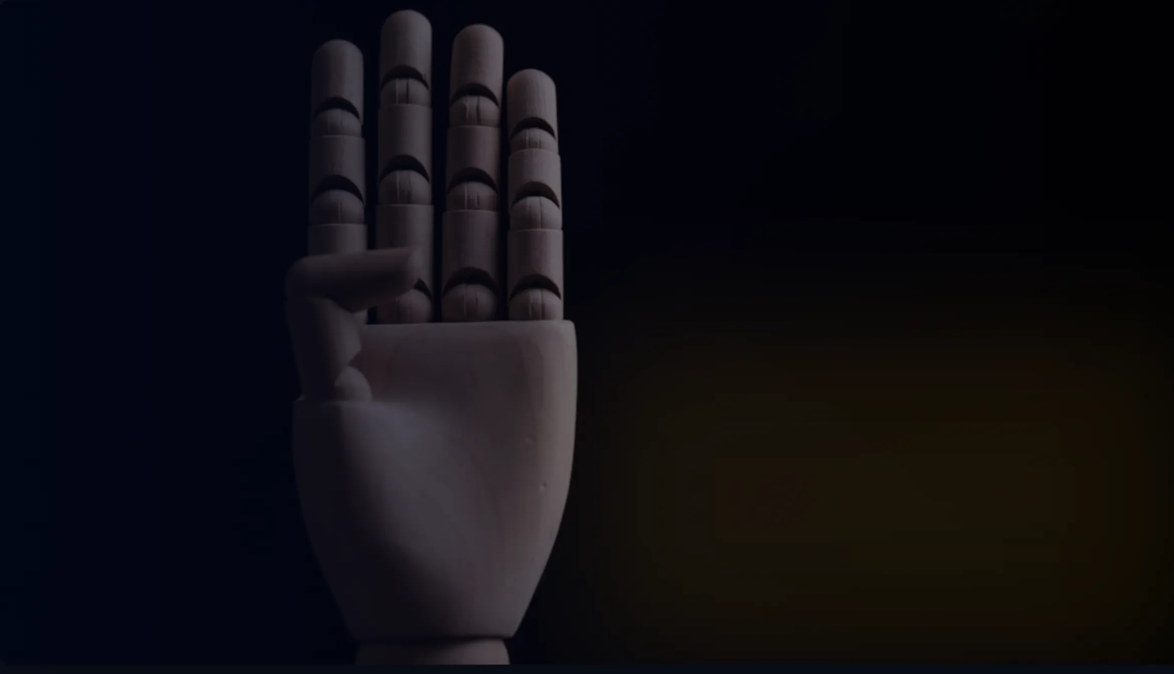 Wooden mannequin hand raised against a dark background